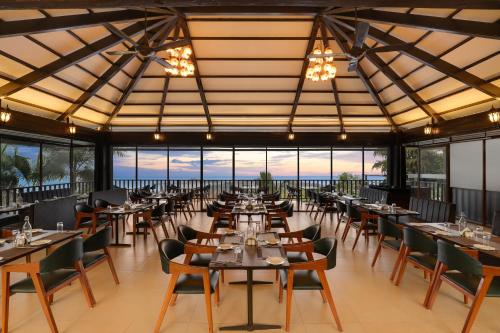 a dining room with tables and chairs and windows at Lemon Tree Hotel, Dapoli in Dapoli