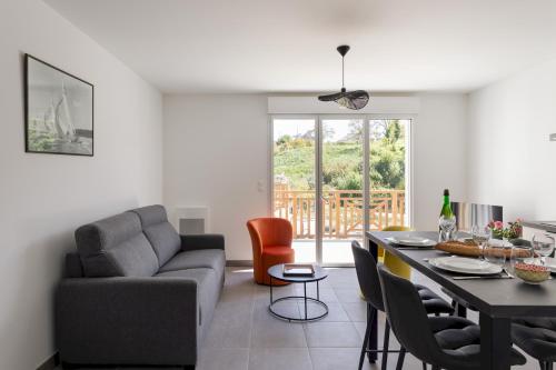 un salon avec un canapé et une table avec des chaises dans l'établissement Les pins 201 - Appt à moins dun km de la plage, à Fréhel