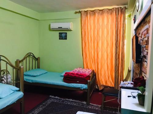 a room with two beds and an orange curtain at Millat Hotel & Noor Jahan Hotel Kandahar in Kandahār
