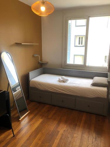 a bedroom with a bed with a window and a mirror at Chambre meublée café boulevard Joseph vallier in Grenoble