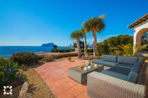 テウラーダにあるVilla Blue Sea by Abahana Villasの青いソファとテーブル付きのパティオ