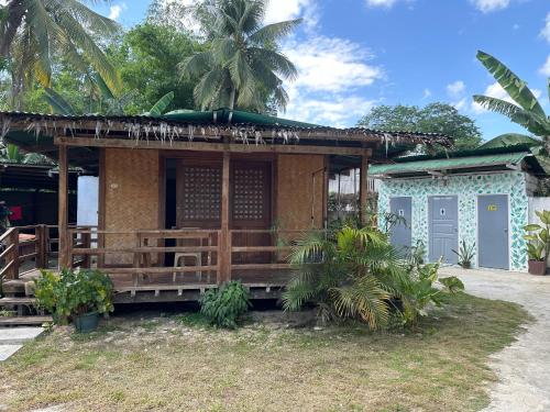 a small house with a wooden porch and palm trees at Tribal Xperience Guesthouse in San Vicente
