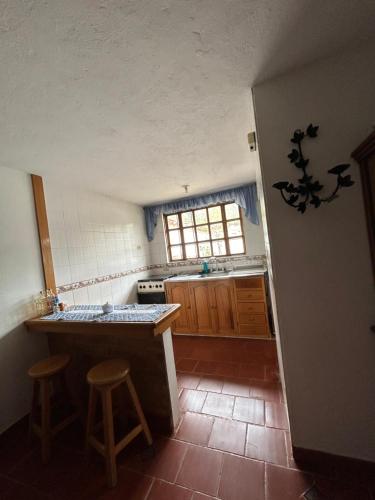 una cocina con barra y dos taburetes. en Acogedora casa en Villa de Leyva, en Villa de Leyva
