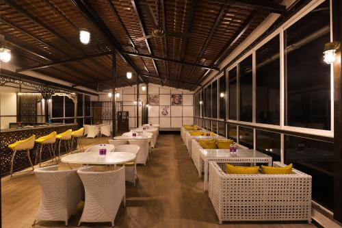 a restaurant with white tables and yellow chairs at Lemon Tree Hotel, Dapoli in Dapoli