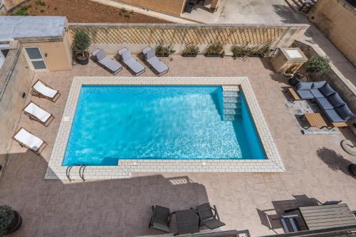 an overhead view of a swimming pool with chaise lounge chairs at Tranquil Mansion - 3 Bed, Pool, BBQ & Gaming Room in Is-Swieqi
