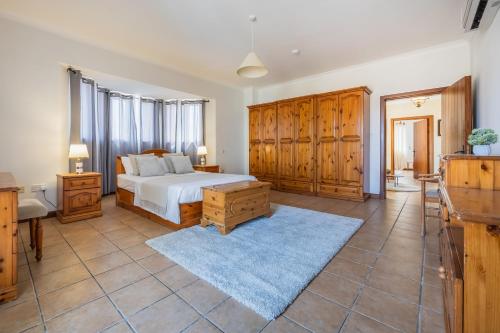 a bedroom with a bed and wooden cabinets at Tranquil Mansion - 3 Bed, Pool, BBQ & Gaming Room in Is-Swieqi