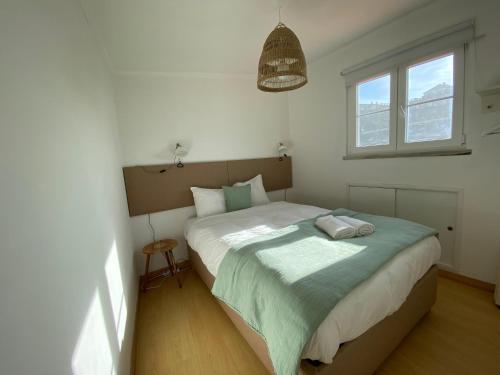 1 dormitorio con 1 cama con manta verde y 2 ventanas en Azenhas do Mar Beach House, en Sintra