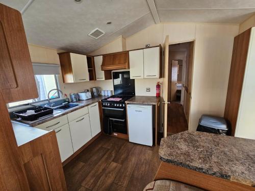 a small kitchen with white appliances and wooden cabinets at NEW Orla Caravan in Meliden