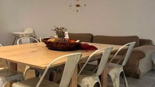 een houten tafel met stoelen en een kom ananas erop bij Apartamento Agost Illes Balears in Ibiza-stad