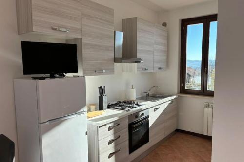 uma cozinha com um frigorífico branco e uma televisão em Casa al Poggio em Castana