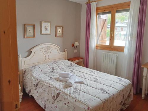 1 dormitorio con 1 cama con edredón blanco y ventana en Apartamentos Gavín Biescas 3000, en Gavín