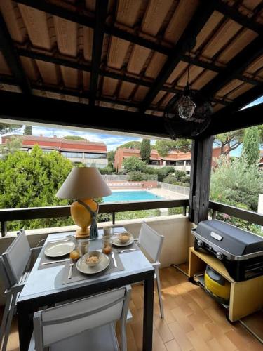 d'une table et de chaises sur un balcon avec barbecue. dans l'établissement Duplex avec piscine, parking et proche des plages, à Fréjus
