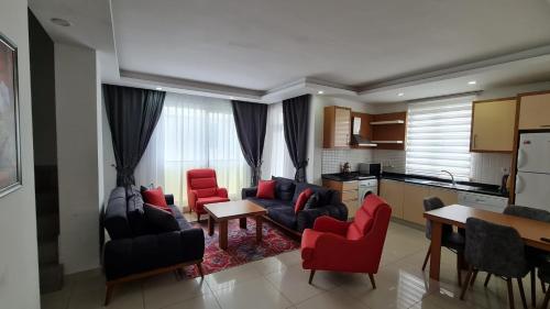 a living room with red chairs and a kitchen at AQUA CİTY SUİT in Antalya