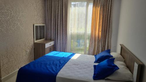 a bedroom with a bed with blue pillows and a window at AQUA CİTY SUİT in Antalya