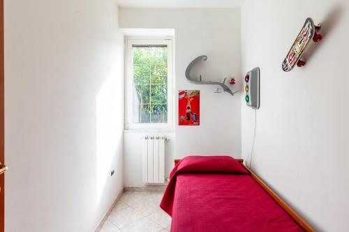 Habitación con cama roja y ventana en Casa vacanza Massa, en Massa