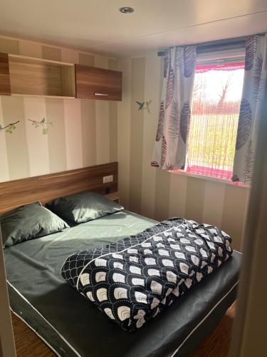 a bedroom with a bed and a window at Mobilhome camping proche des plages in Saint-Jean-de-Monts