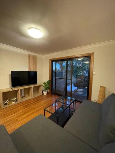 a living room with a couch and a flat screen tv at Comfortable 3 Bedroom House Pyrmont in Sydney