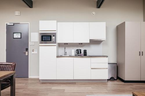 a kitchen with white cabinets and a sink at YAYS Amsterdam Maritime by Numa in Amsterdam