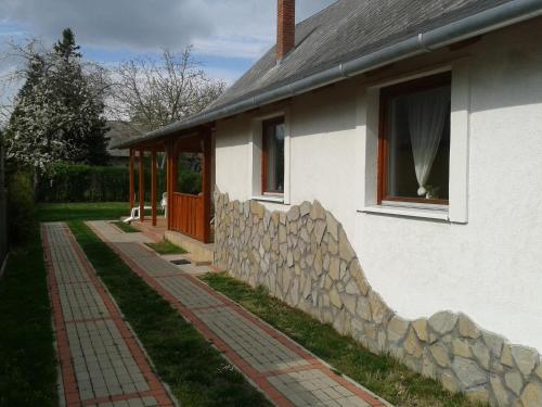 a white house with a stone wall and a window at Munkácsy Apartmanok in Balatonfenyves