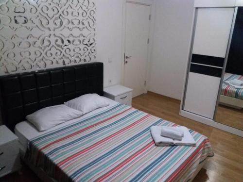 a bedroom with a bed with a striped blanket and a mirror at AQUA CİTY SUİT in Antalya