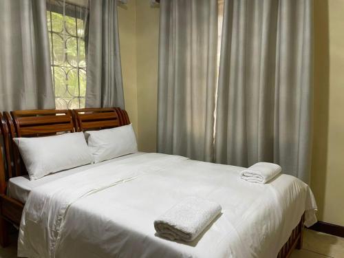 ein Bett mit zwei Handtüchern darauf vor einem Fenster in der Unterkunft Tranquility three bedroom house with Wi-Fi in Daressalam