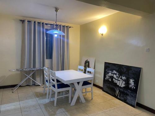 a dining room with a white table and chairs at Tranquility three bedroom house with Wi-Fi in Dar es Salaam