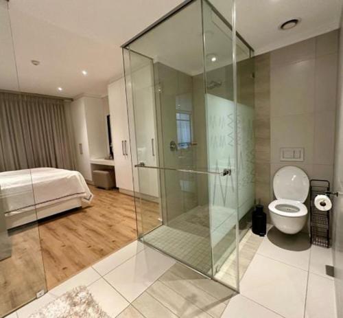 a bathroom with a shower and a toilet and a bed at Cosy Executive Hotel Room (SA) in Johannesburg
