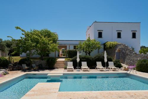 a pool with chairs and a house in the background at Masserie Maresca in Ostuni