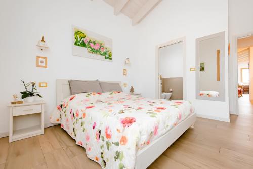 フマーネにあるB&B Mimosa e Lillàの白いベッドルーム(花柄のベッドカバー付)