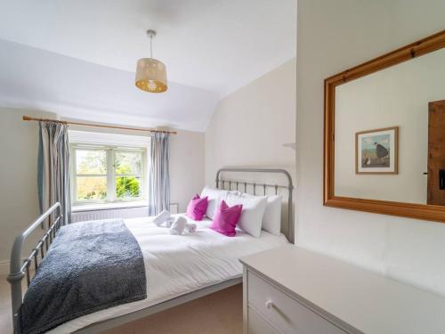 una camera da letto con letto, cuscini rosa e specchio di Pass the Keys Unicorn Cottage Rural Cotswold Escape a Great Rollright