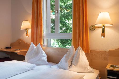 a bedroom with a bed with pillows and a window at Hotel Bellevue - Traditional Swiss Hideaway in Wengen