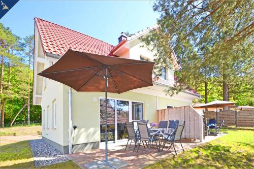 a large brown umbrella in front of a house at Waldsiedlung DHH Waldhaus 6 in Korswandt