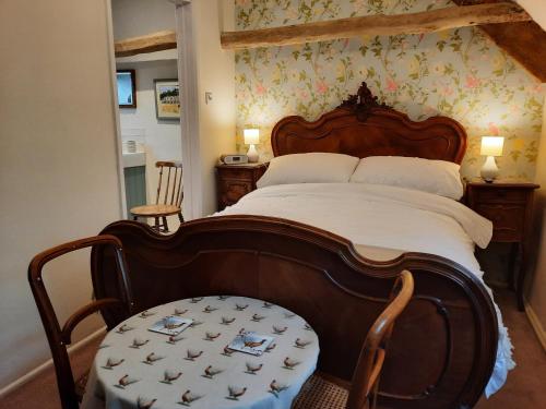 een slaapkamer met een groot bed met een houten hoofdeinde bij Cotswold Cottage Bed & Breakfast in Luckington