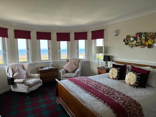 1 Schlafzimmer mit einem Bett, 2 Stühlen und Fenstern in der Unterkunft Beaches in Ayr