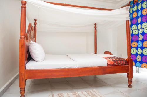 a bedroom with a wooden bed with white sheets at KaribuGuestHouse in Fort Portal
