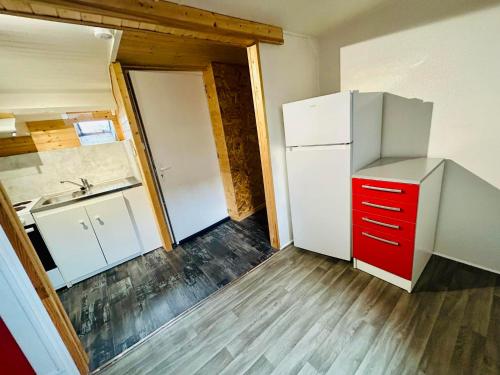 a kitchen with a white refrigerator and a red drawer at appartement 2 pieces in Aurillac