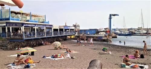 eine Gruppe von Menschen am Strand in der Nähe eines Piers in der Unterkunft Balcon del sur con vista mar in Arona