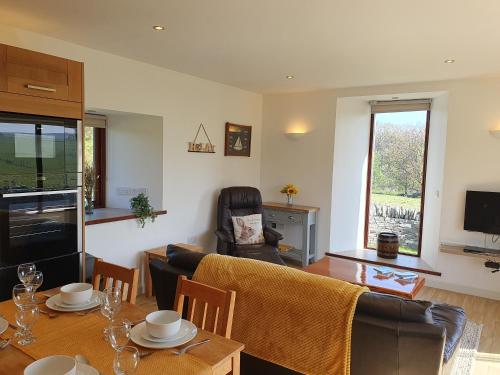 a living room with a table and a couch at Woodwick Mill Cottage in Evie