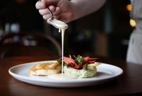 una persona está vertiendo salsa en un plato de comida en Hotel Aurlandsfjord, en Aurland