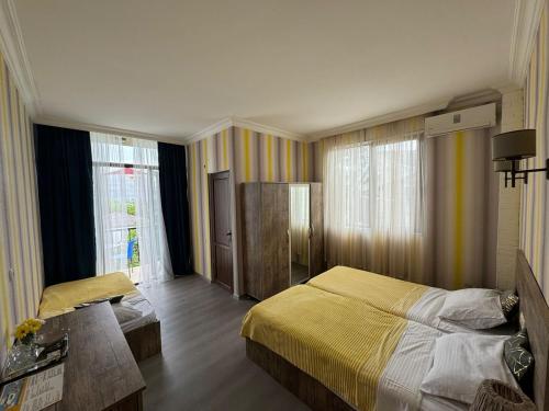 Schlafzimmer mit einem Bett, einem Tisch und Fenstern in der Unterkunft Terassa Hotel Kobuleti in Kobuleti