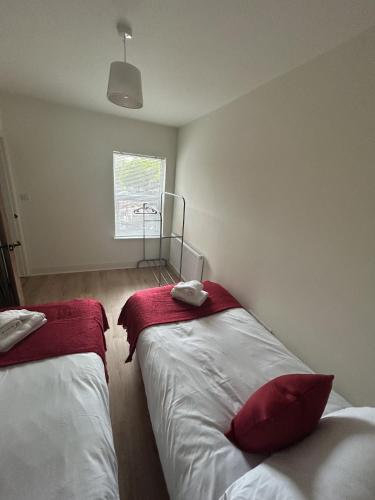 una camera con due letti con lenzuola rosse e una finestra di Kensington Park a Reading