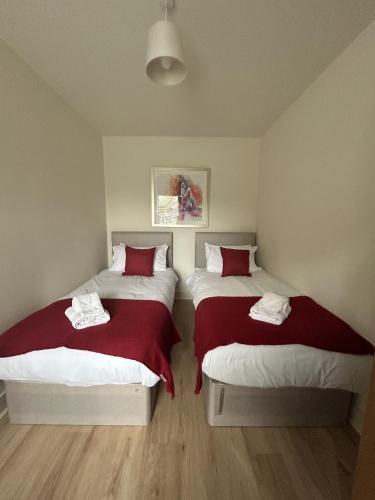 a bedroom with two beds with red and white sheets at Kensington Park in Reading