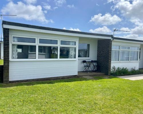a house with a garage with a grass yard at Modern Airy Chalets short walk to beach, Nr Norfolk Broads & Great Yarmouth in Scratby