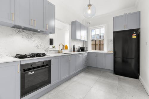 a kitchen with white cabinets and a black refrigerator at Perfect 2BR Harbour View Apartment in Sydney