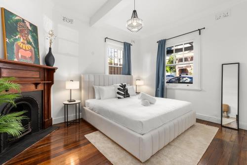 a bedroom with a white bed and a fireplace at Perfect 2BR Harbour View Apartment in Sydney