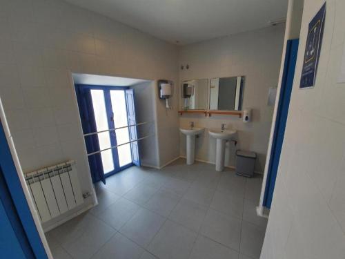 łazienka z 2 toaletami, umywalką i oknem w obiekcie Albergue Villares de Orbigo w mieście Villares de Órbigo