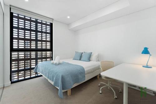 a white bedroom with a bed and a desk at St Leonards 2B2B Apt with Skyview in Sydney