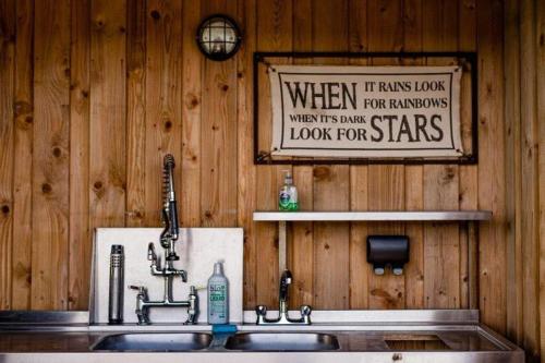 a kitchen sink with a sign on a wooden wall at 7, Rabbits Run, Camp Tapnell in Yarmouth