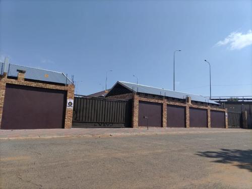 a brick building with two garage doors on a street at Lukhanya Guesthouse in Randfontein