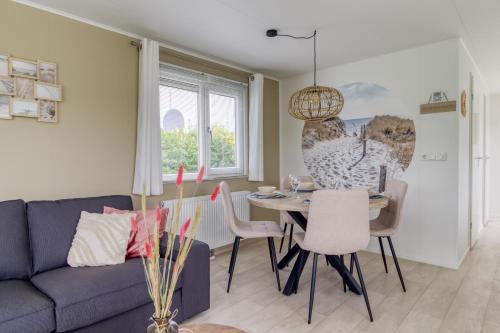 a living room with a couch and a table and chairs at Chalet aan zee in Retranchement